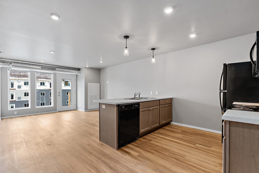 an open kitchen and living room with wood flooring and a large window