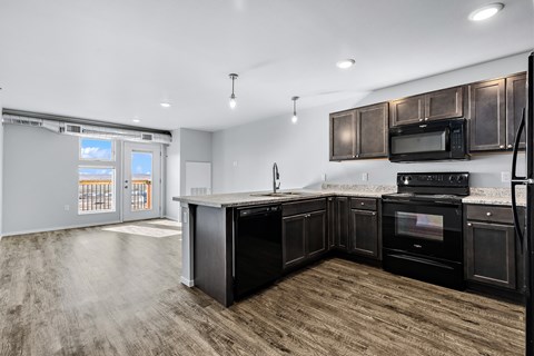 an open kitchen and living room with dark wood cabinets and stainless steel appliances