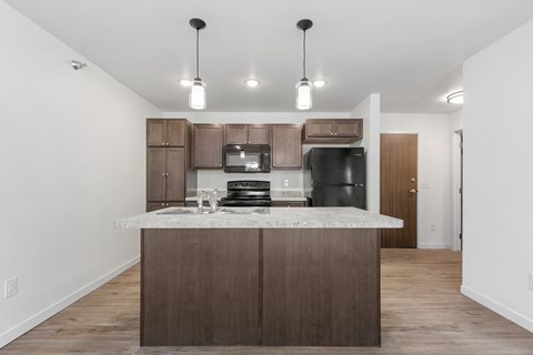 a kitchen with a marble counter top and a black refrigerator