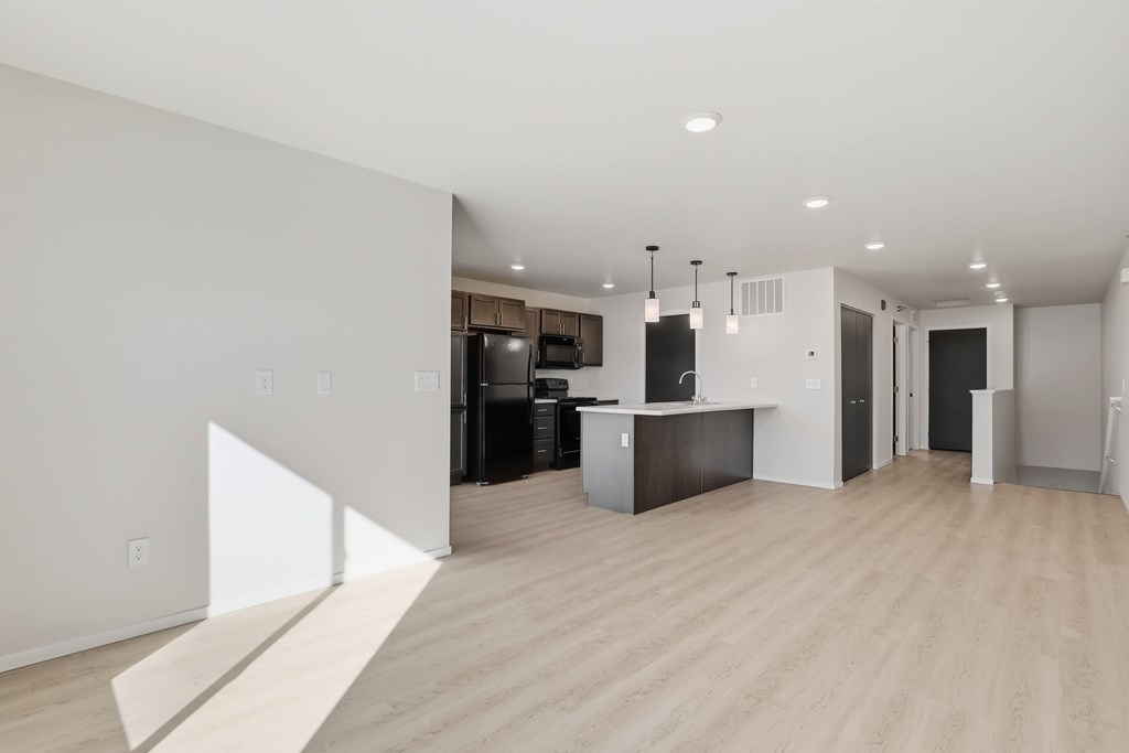 A modern kitchen with a white wall and wooden flooring.