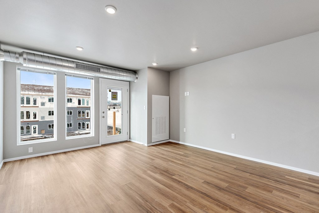 an empty living room with a large window and wood flooring