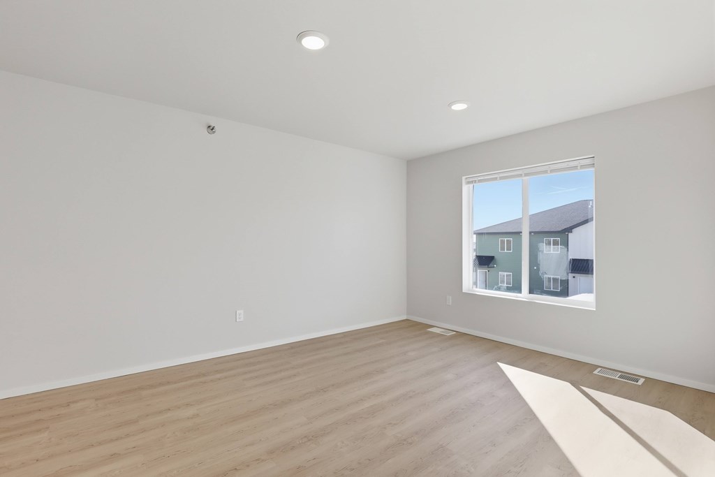 A room with a window and wooden flooring.
