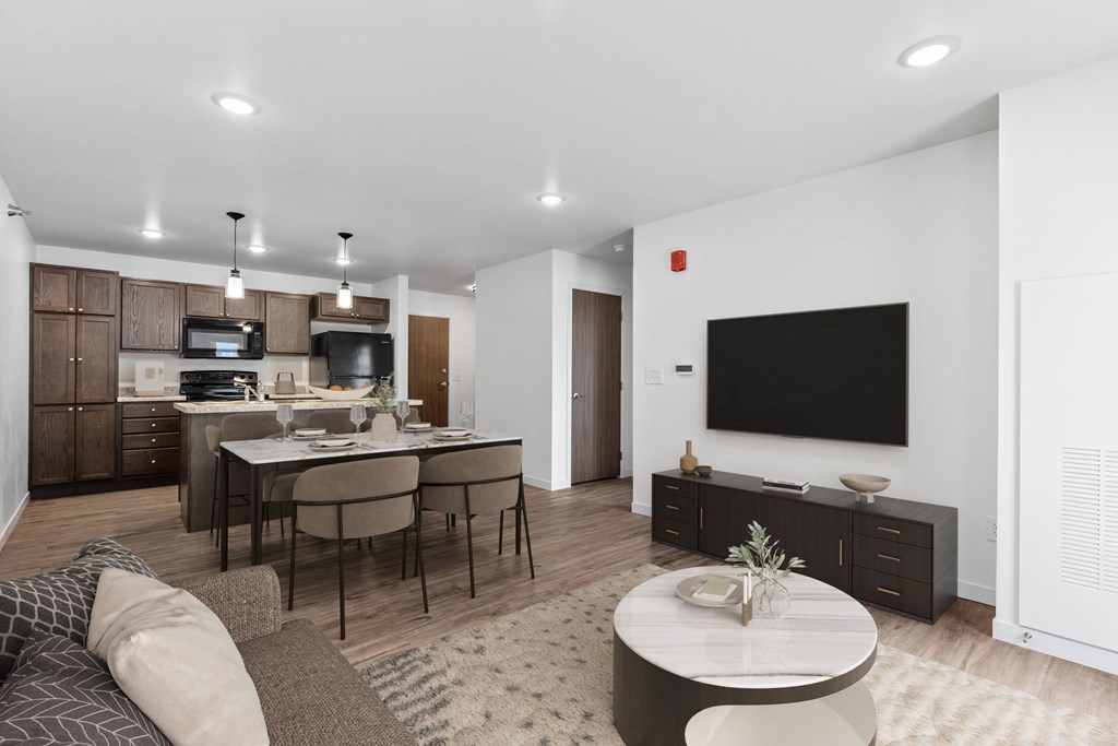 A modern living room with a kitchen area in the background.