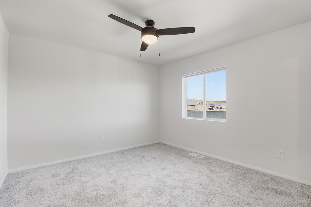A room with a ceiling fan and a window with a view of the outside.