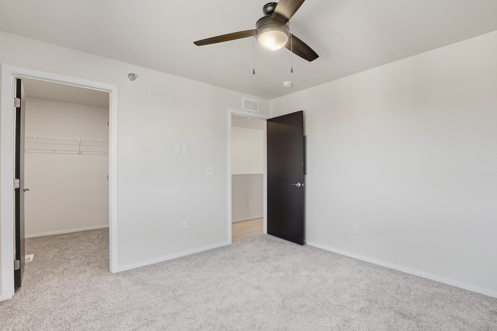 A room with a ceiling fan and a black door.