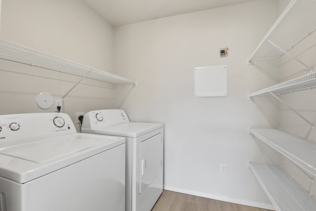 A laundry room with two washing machines and a shelf.