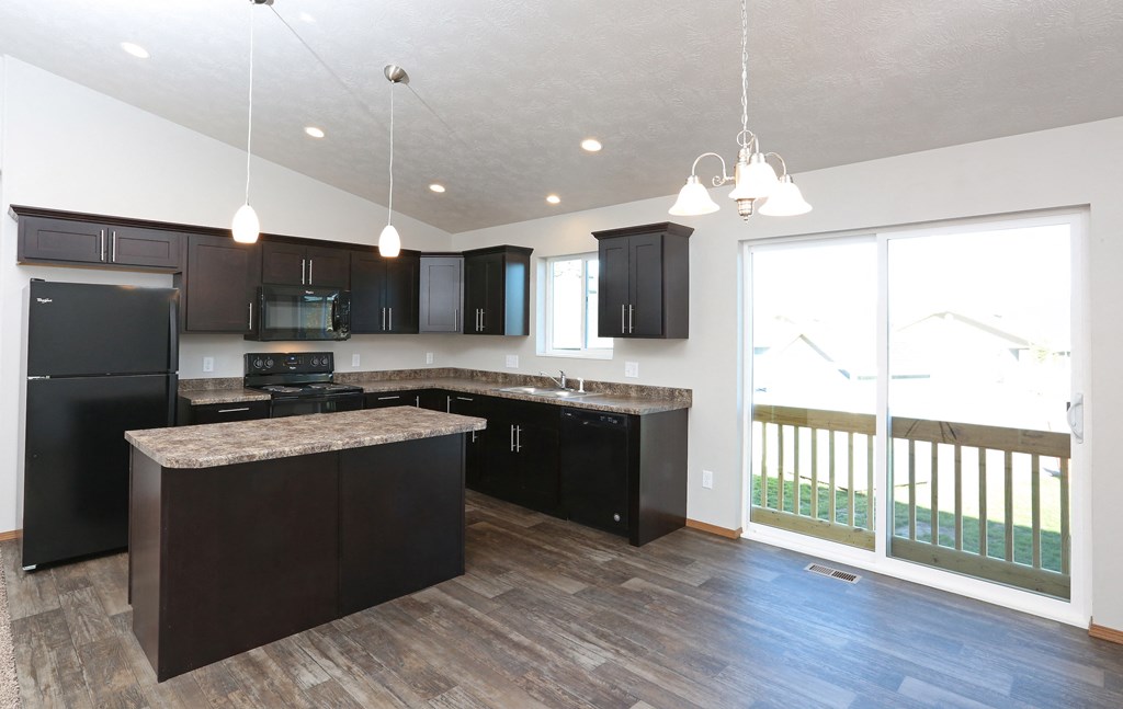 an empty kitchen with black cabinets and a large window