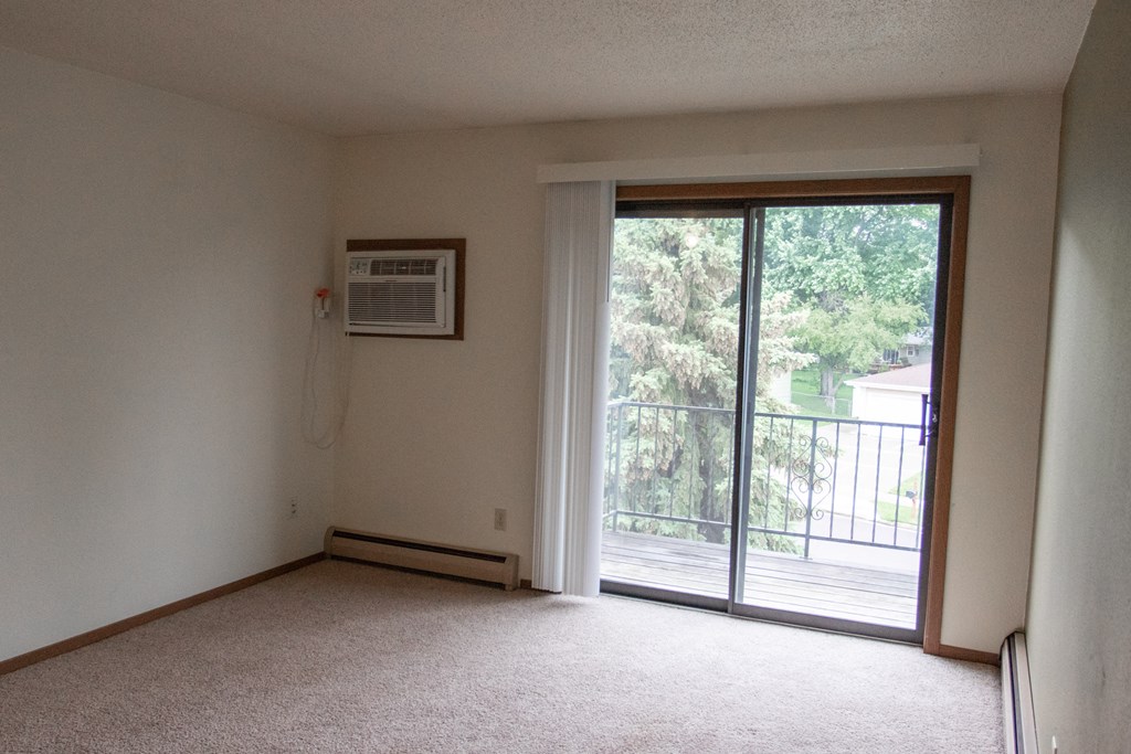 an empty living room with a door to a balcony