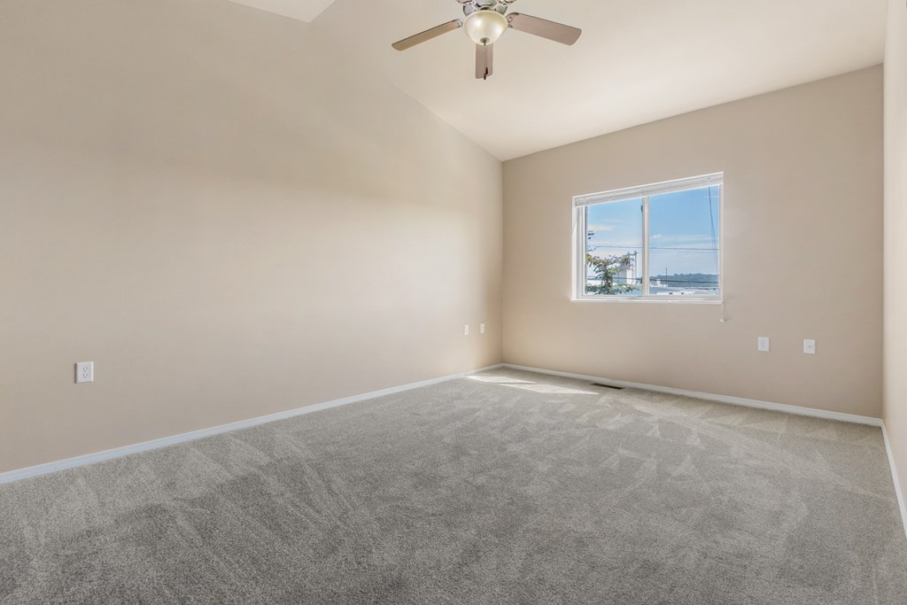 A room with a ceiling fan and a window overlooking the beach.