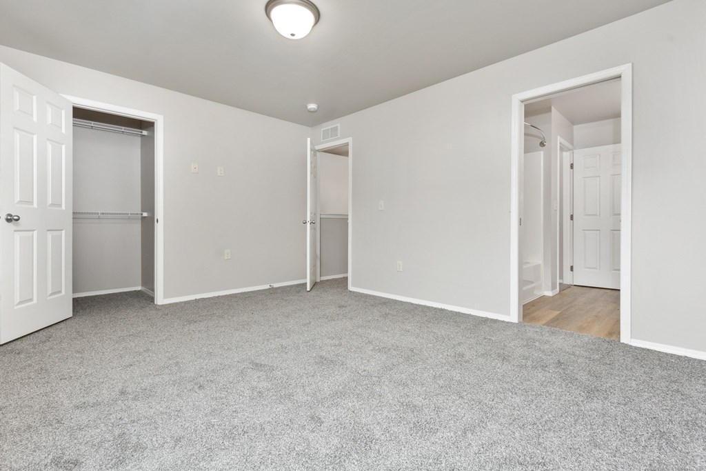 A spacious room with white walls and carpeted floor.