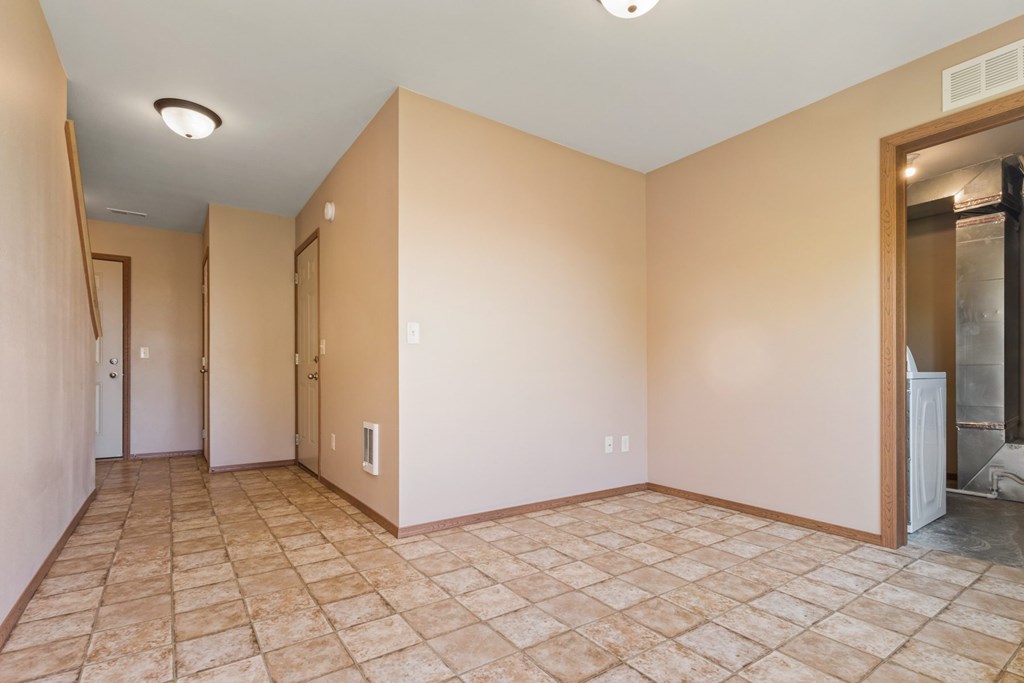 A room with tiled flooring and a refrigerator in the corner.