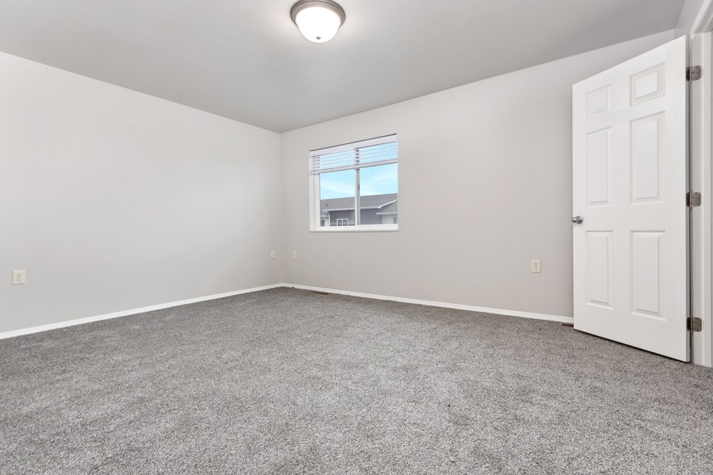 A room with a carpeted floor and a window.