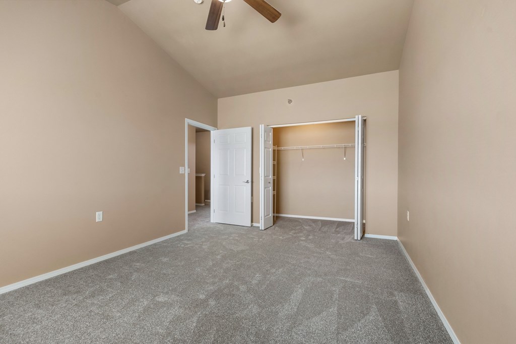 A room with a carpeted floor and a ceiling fan.