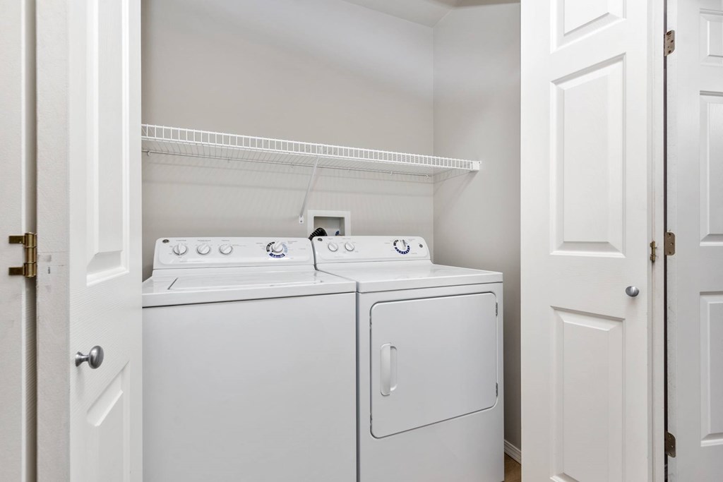 Two white washing machines in a small laundry room.