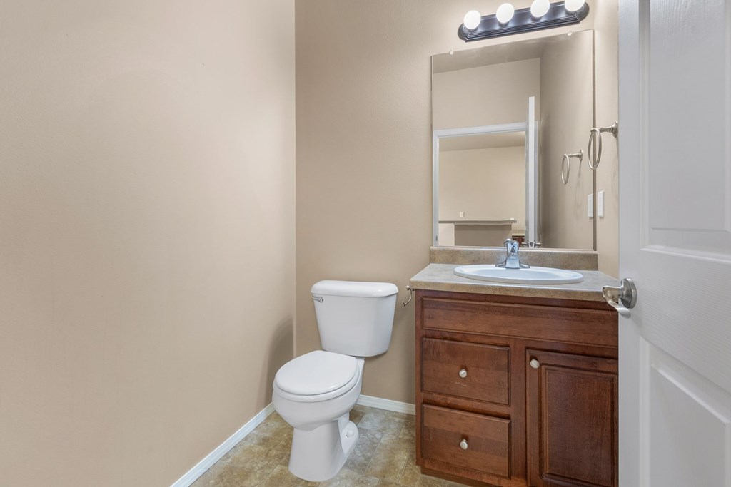 A bathroom with a toilet, sink, and mirror.