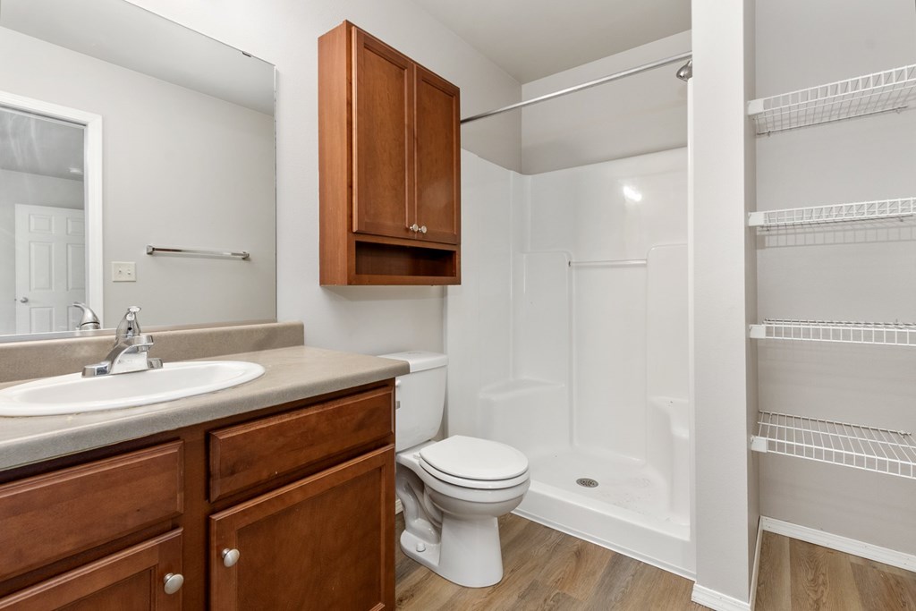 A white bathroom with a toilet, sink, and a walk-in shower.