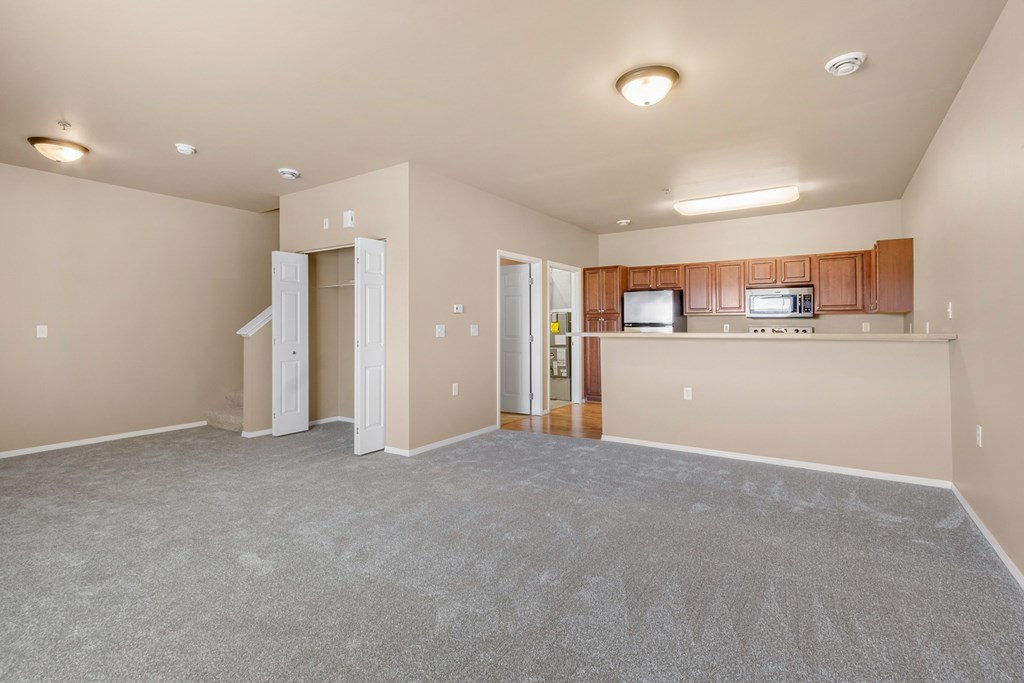 A spacious living room with a kitchen area in the background.