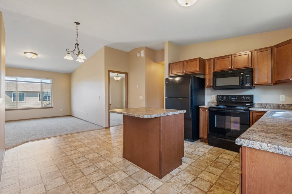 A kitchen with black appliances and wooden cabinets.