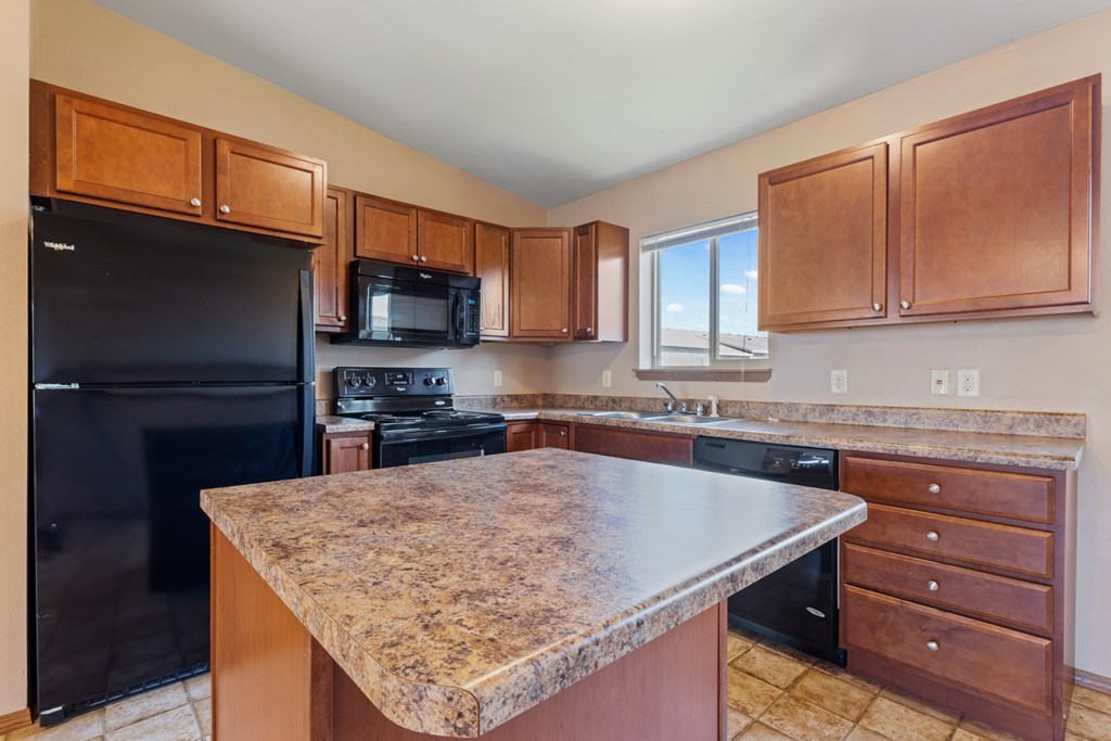 A kitchen with a granite countertop and wooden cabinets.
