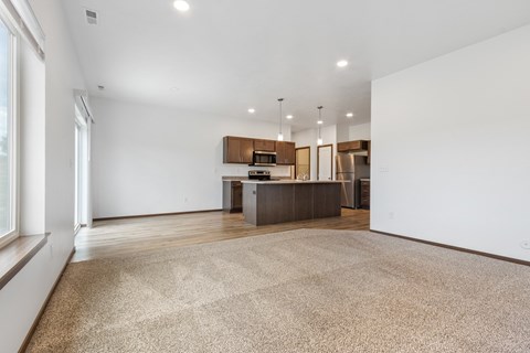A spacious kitchen and living room with a large rug on the floor.