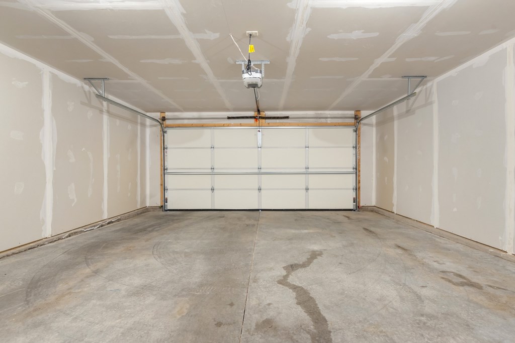 A garage with a white door and a concrete floor.