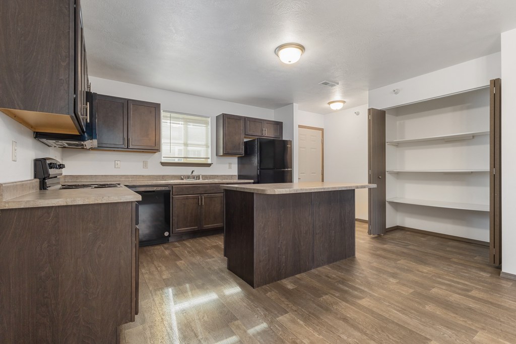 A kitchen with brown cabinets and a wooden floor.