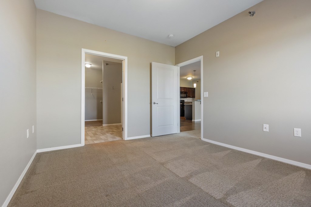 A room with carpeted floor and two open doors.