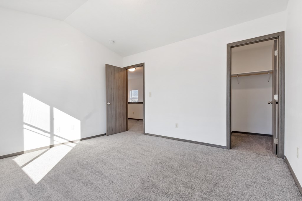 A large, empty room with a carpeted floor and a door on the right side.