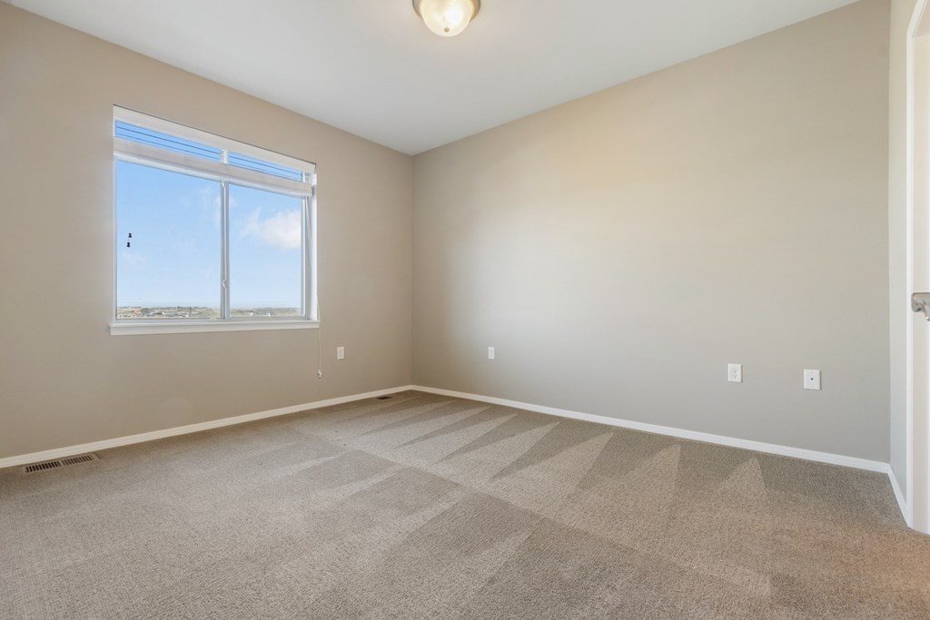 A room with a carpeted floor and a window.