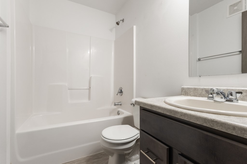 A white toilet sits next to a white bathtub in a bathroom.