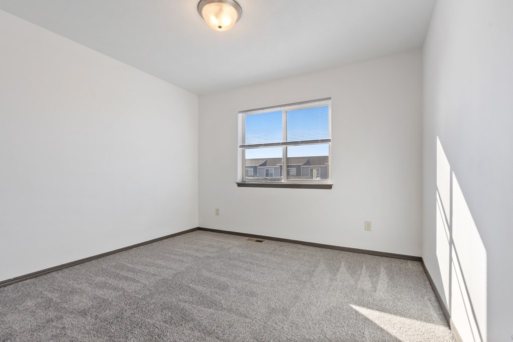 A room with a carpeted floor and a window overlooking a building.