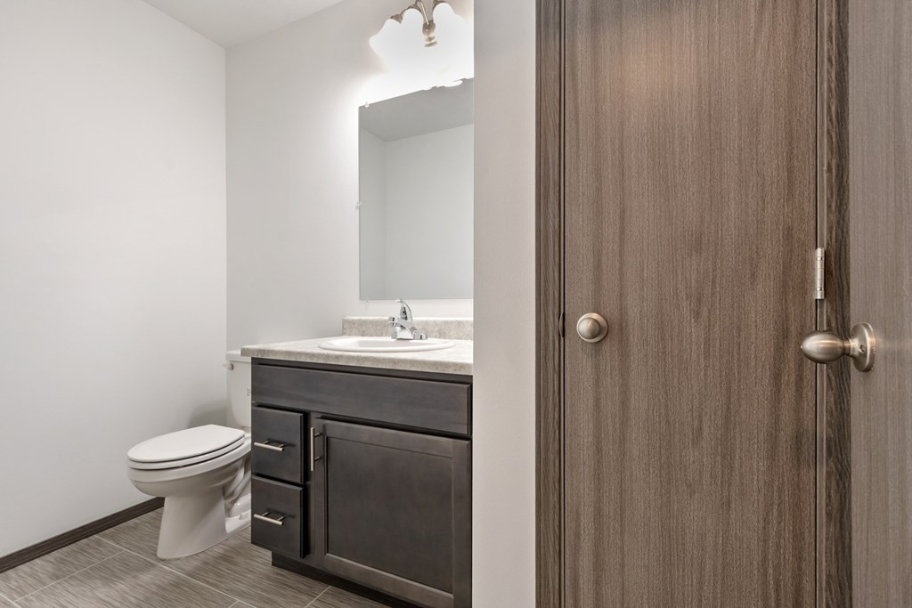 A bathroom with a toilet, sink, and mirror.