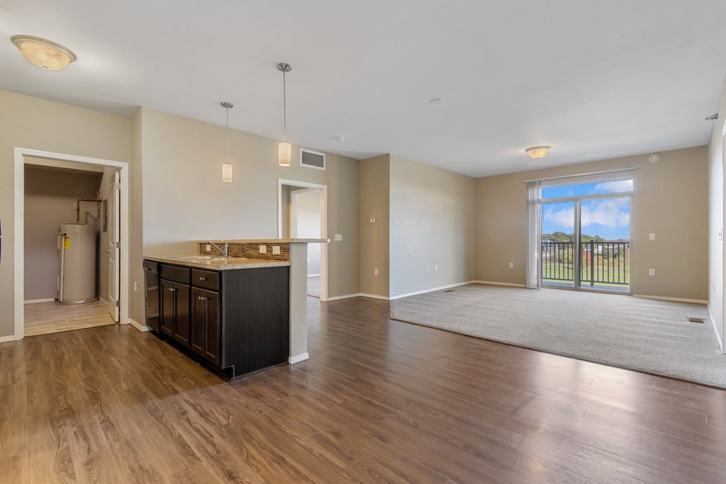 A spacious living room with a kitchen area in the background.