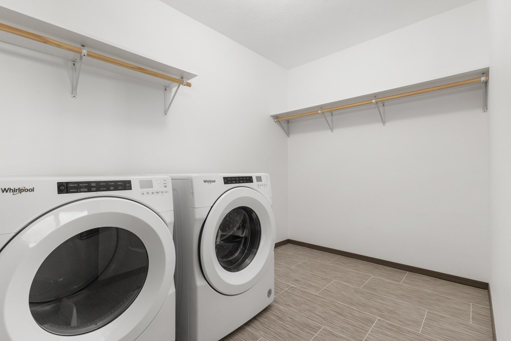 Two white front loading washing machines in a laundry room.