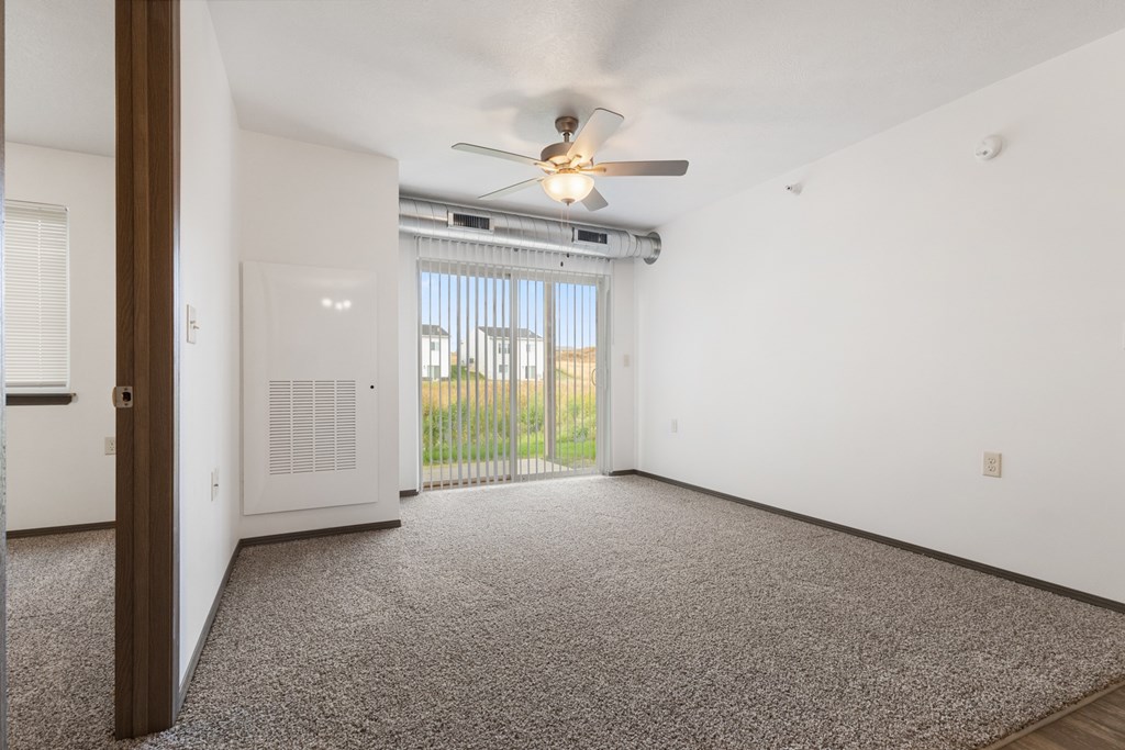 A room with a ceiling fan and a window with blinds.
