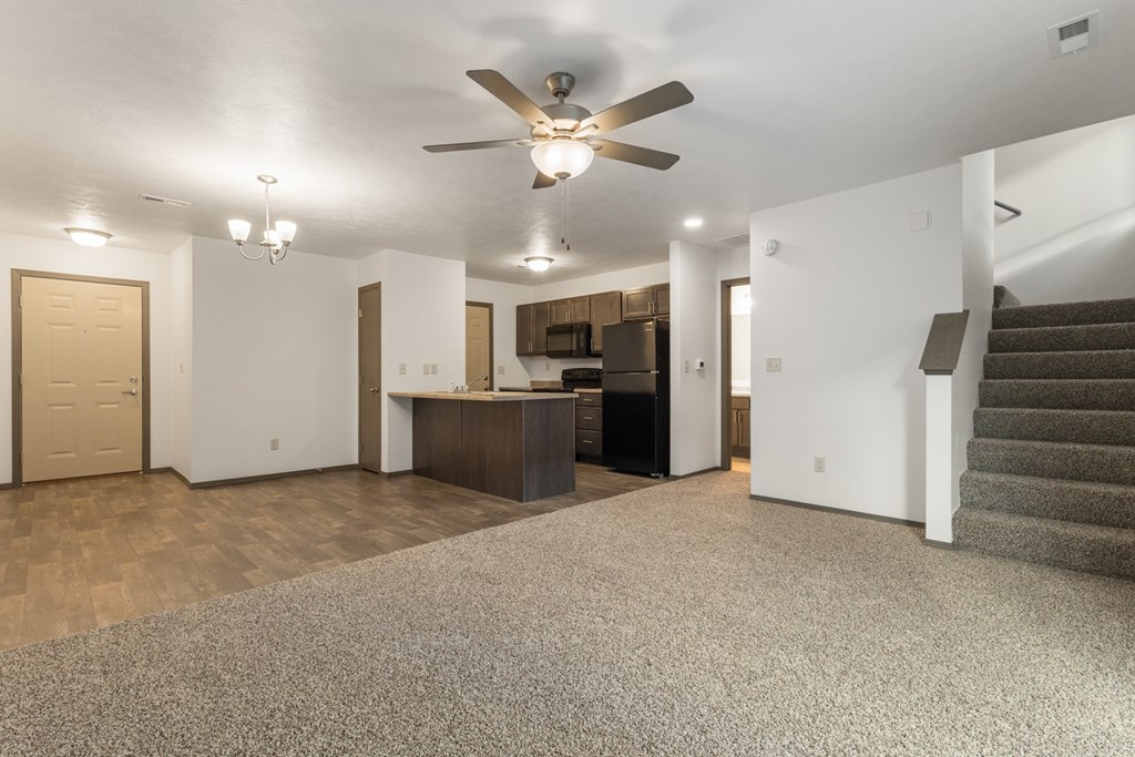 A spacious living room with a staircase on the right side.