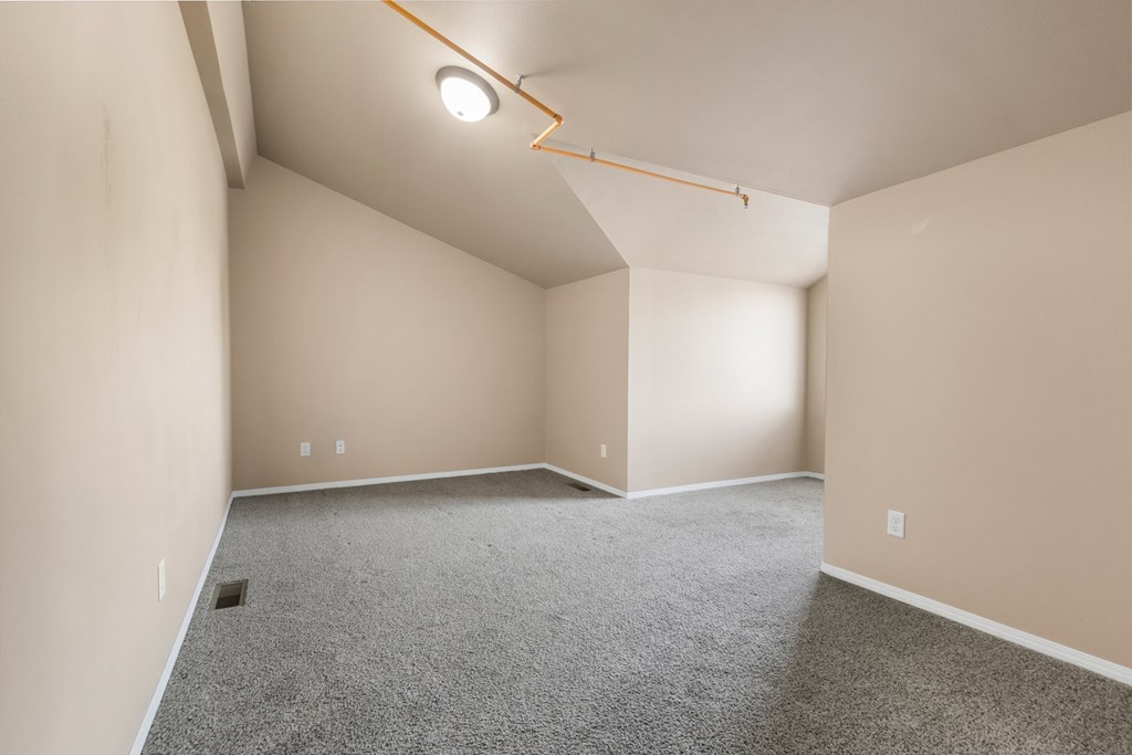 A room with a carpeted floor and a single light fixture on the ceiling.