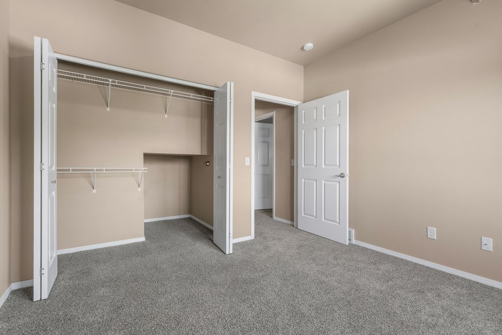 A room with a white door and a white closet with a shelf.