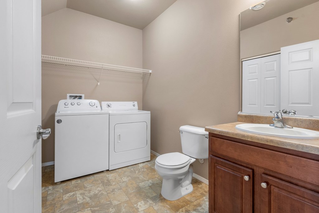 A bathroom with a toilet, sink, and washer and dryer.