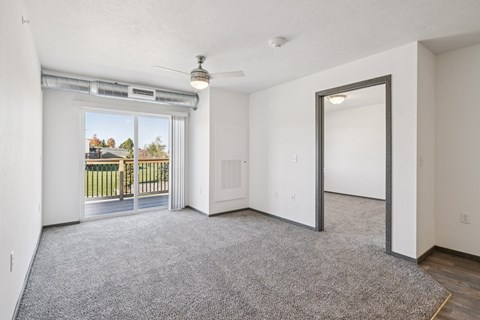 A room with a grey carpet and a sliding glass door leading to a balcony.