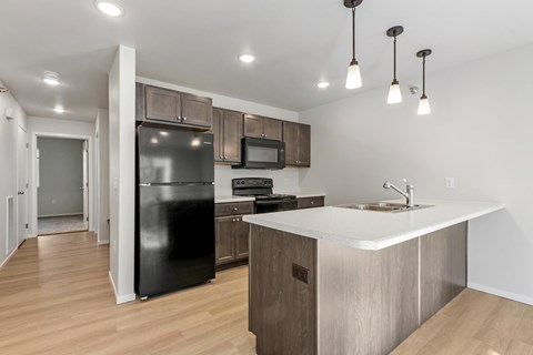 A kitchen with a black fridge, microwave, and stove top oven.