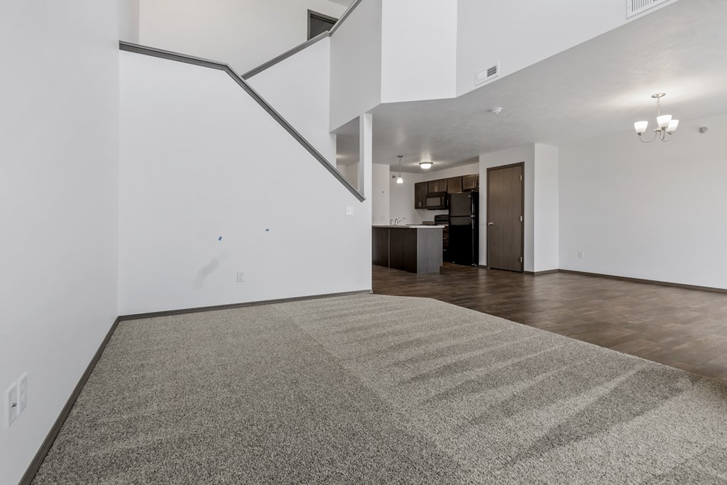 A room with a carpeted floor and a staircase.