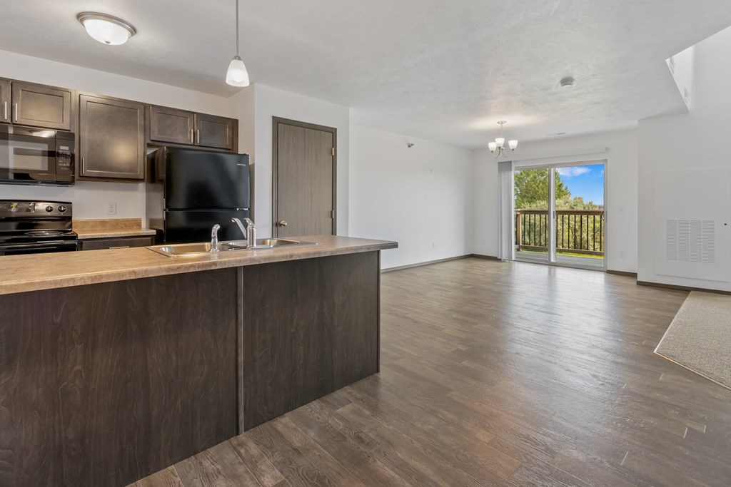 A kitchen with dark wood cabinets and a black fridge.