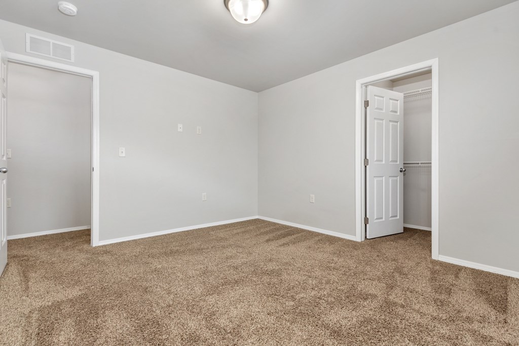 A room with carpeted floor and two doors.