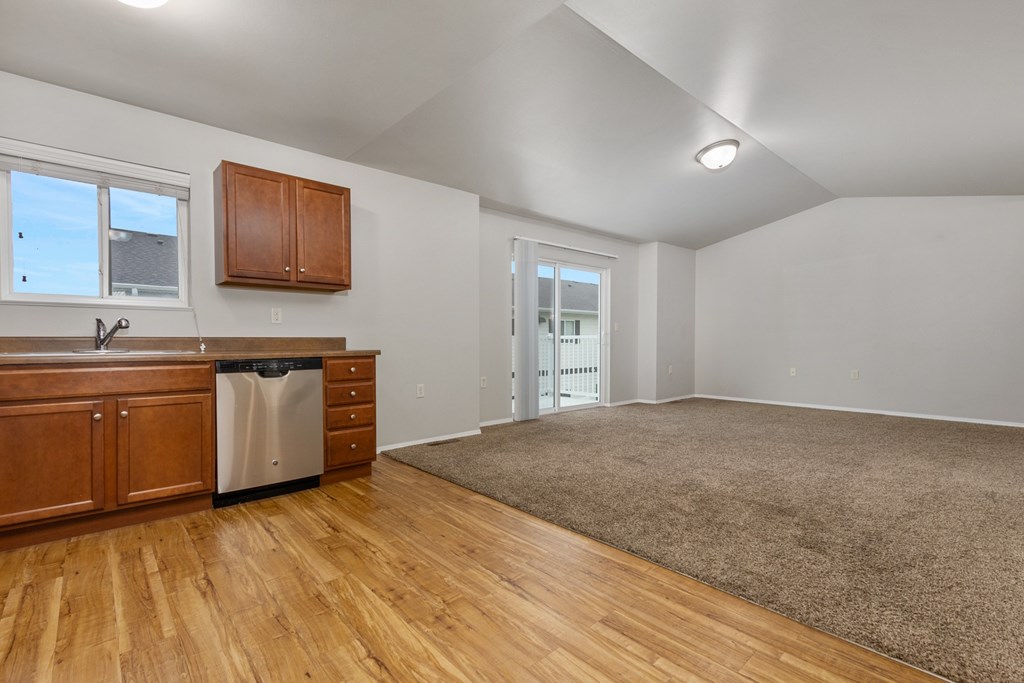 A kitchen with wooden cabinets and a stainless steel dishwasher.