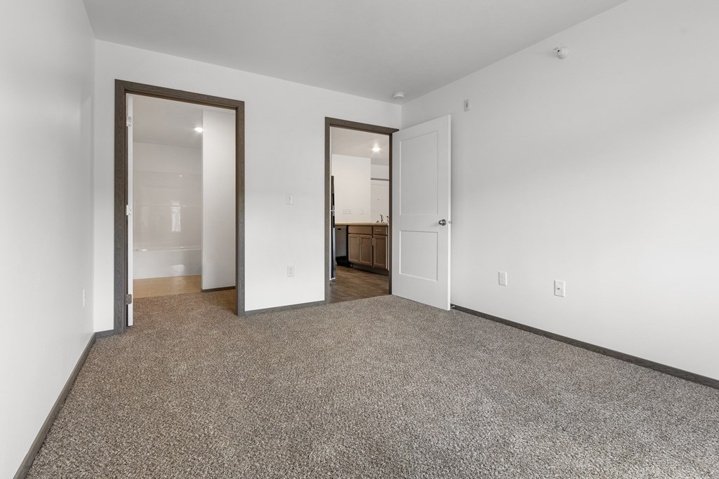 A room with a carpeted floor and two open doors.
