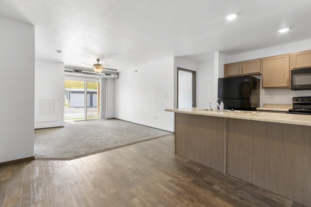 A kitchen area with wooden cabinets and a black microwave.