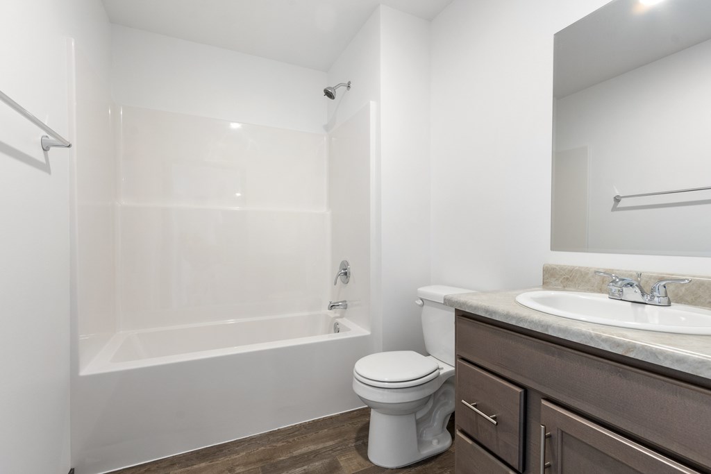 A white toilet sits next to a white bathtub in a bathroom.