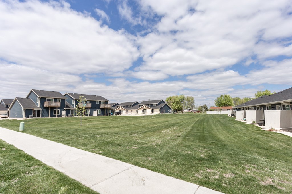 a grass field in front of a row of houses