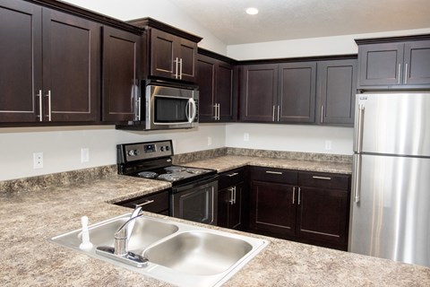 a kitchen with dark cabinets and stainless steel appliances
